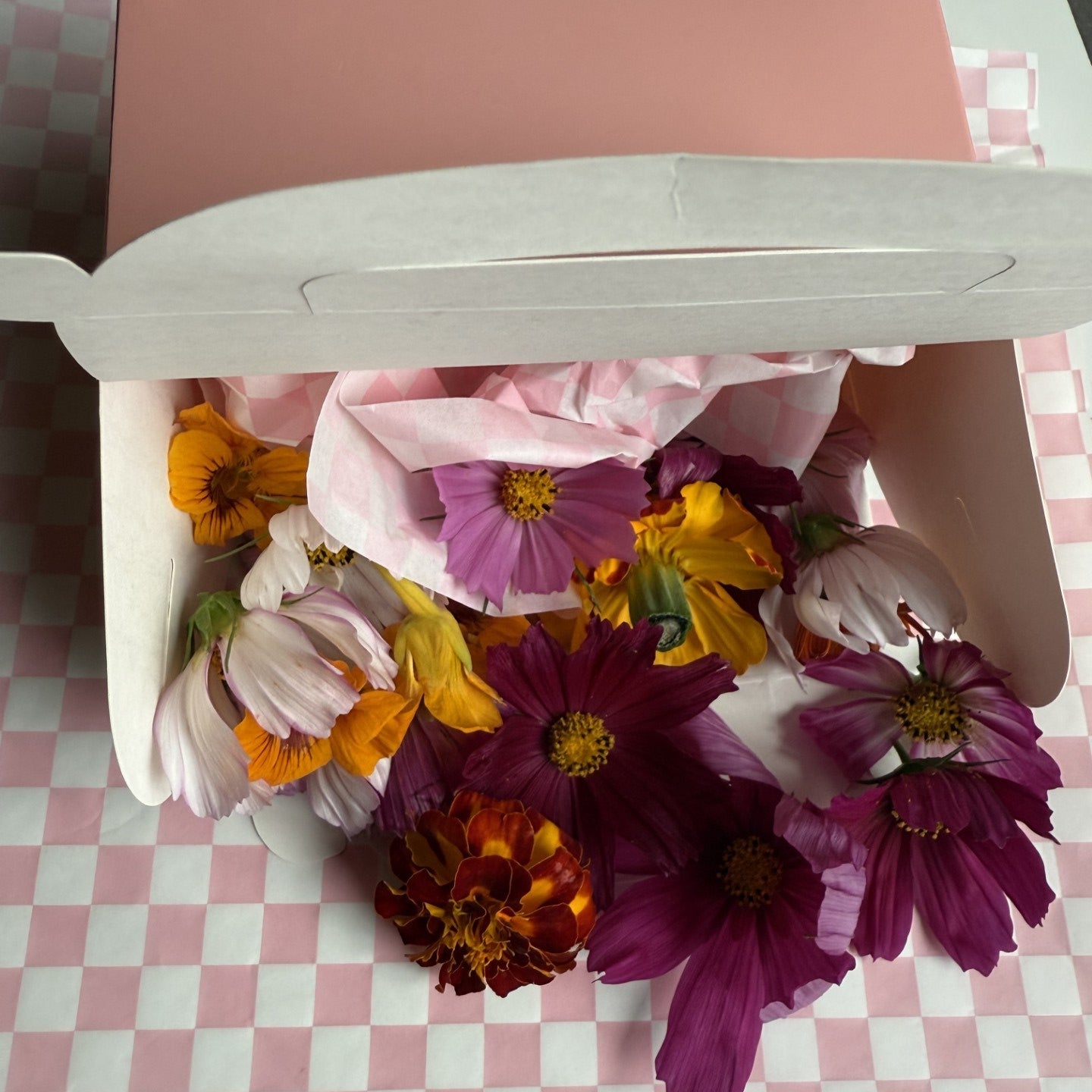 Colorful bouquet of flowers in a pink box on a checkered tablecloth