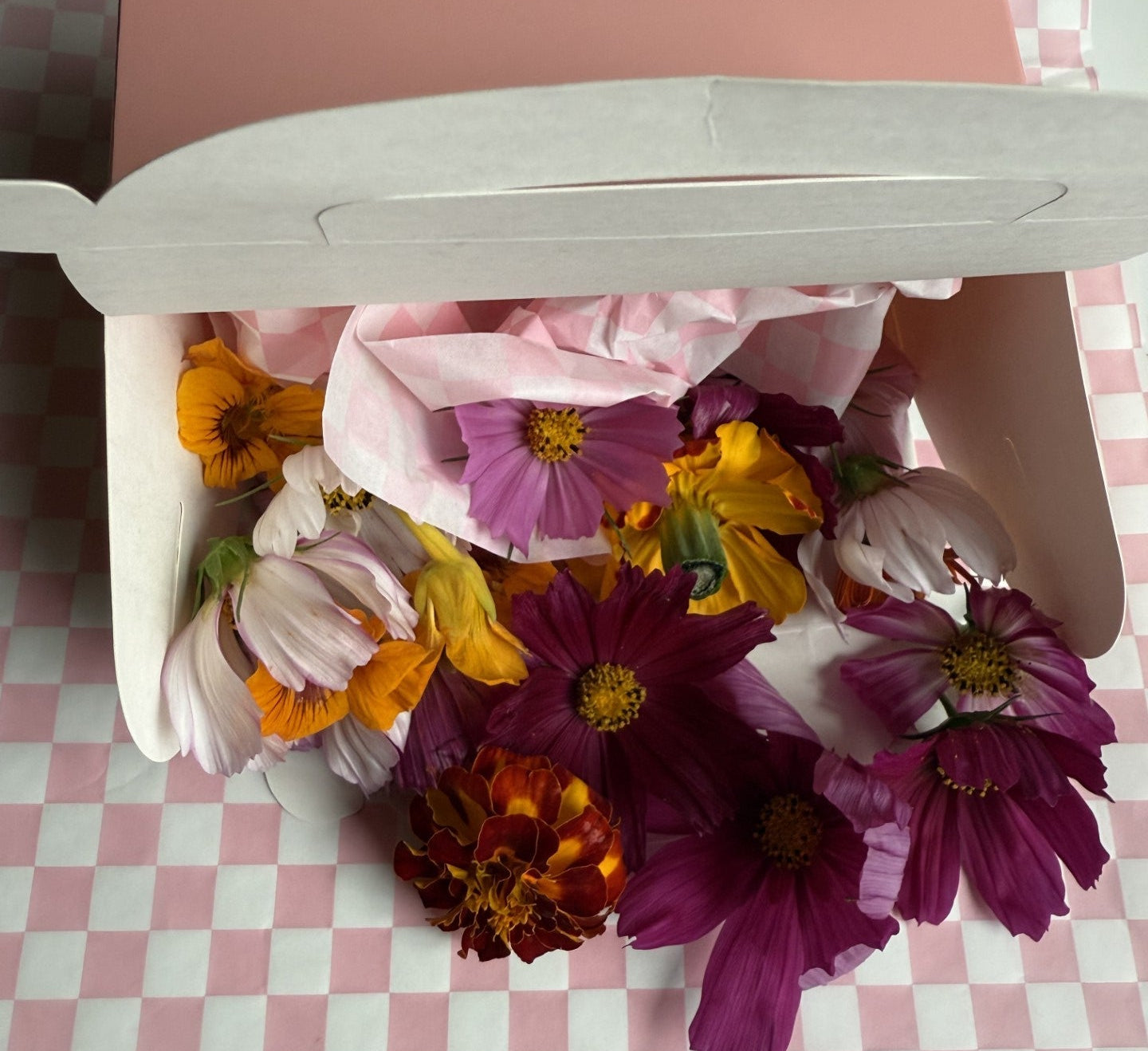 Colorful bouquet of flowers in a pink box on a checkered tablecloth